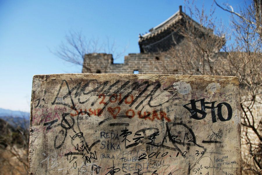 2011年3月27日，初春的北京温暖舒适，户外爱好者攀登慕田峪附近的亓连关长城。一处指路牌的背面写着许多到此一游的名字和话语。