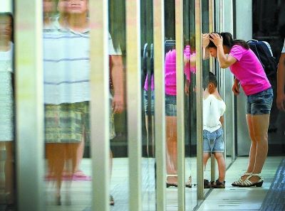 在地铁街道口站，乘客趴在屏蔽门上，此举有危险。