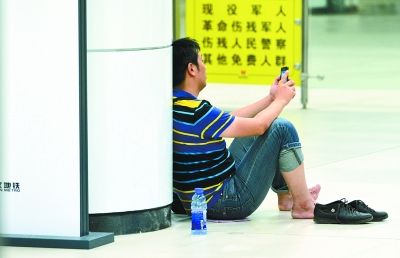 在地铁洪山广场站，一位乘客脱掉鞋子坐在地上。