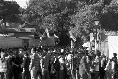 昨日,不少导游聚集在南锣鼓巷南侧路口,等候在胡同内游览购物的随团游客。新京报记者 何光 摄