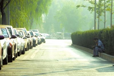 太阳宫中路一名黑停车场管理员在路边休息。京华时报记者潘之望摄