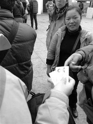 一位“黄牛”(右一)在兜售高价票，游客准备将身份证交给她