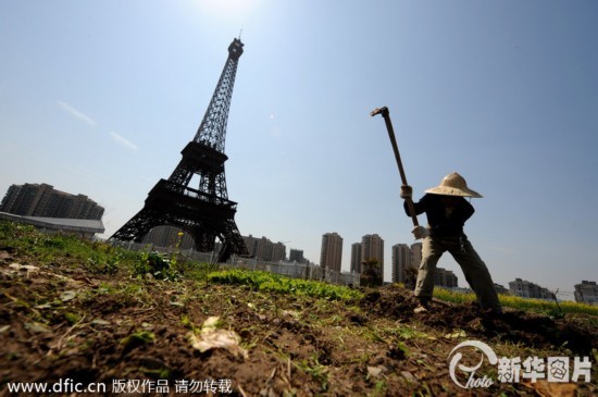 2014年3月21日，杭州天都城，农民在山寨埃菲尔铁塔下耕作。