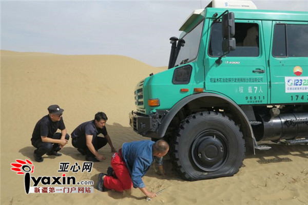 图为:在搜救路上,由于沙山坡高路虚,沙漠车被陷沙海。