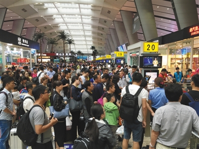 7月下旬，北京南站，旅客在排队候车，背后的候车区域布满商铺。