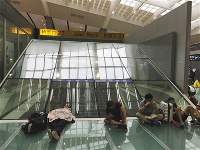 7月下旬，北京南站，旅客在候车大厅席地而坐。